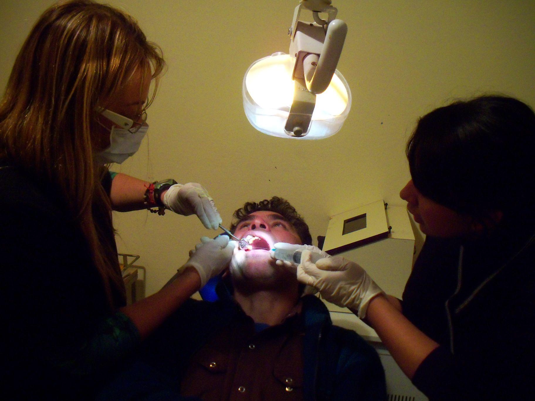 A Medical intern and a staff member of the healthcare centre both examine a patients mouth during a Dentistry internship in Argentina. Projects Abroad Dentistry worker examines a patients mouth with a dentist during Dentistry work experience in Argentina.